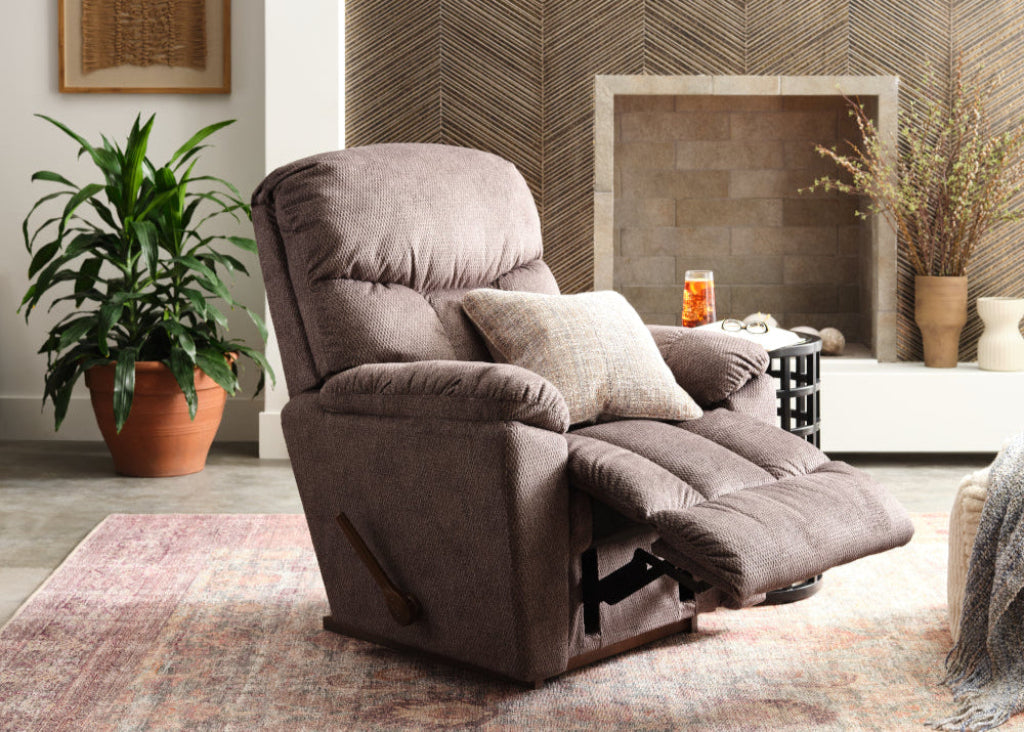 Brown recliner chair in a living room setting with plants and a fireplace.