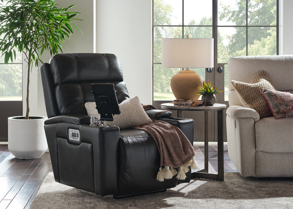 Black recliner chair in a living room with a beige sofa and side table.