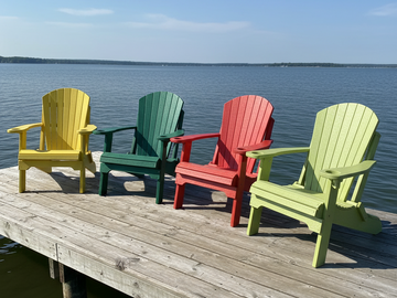 Four colorful Adirondack chairs on a wooden dock by a body of water.