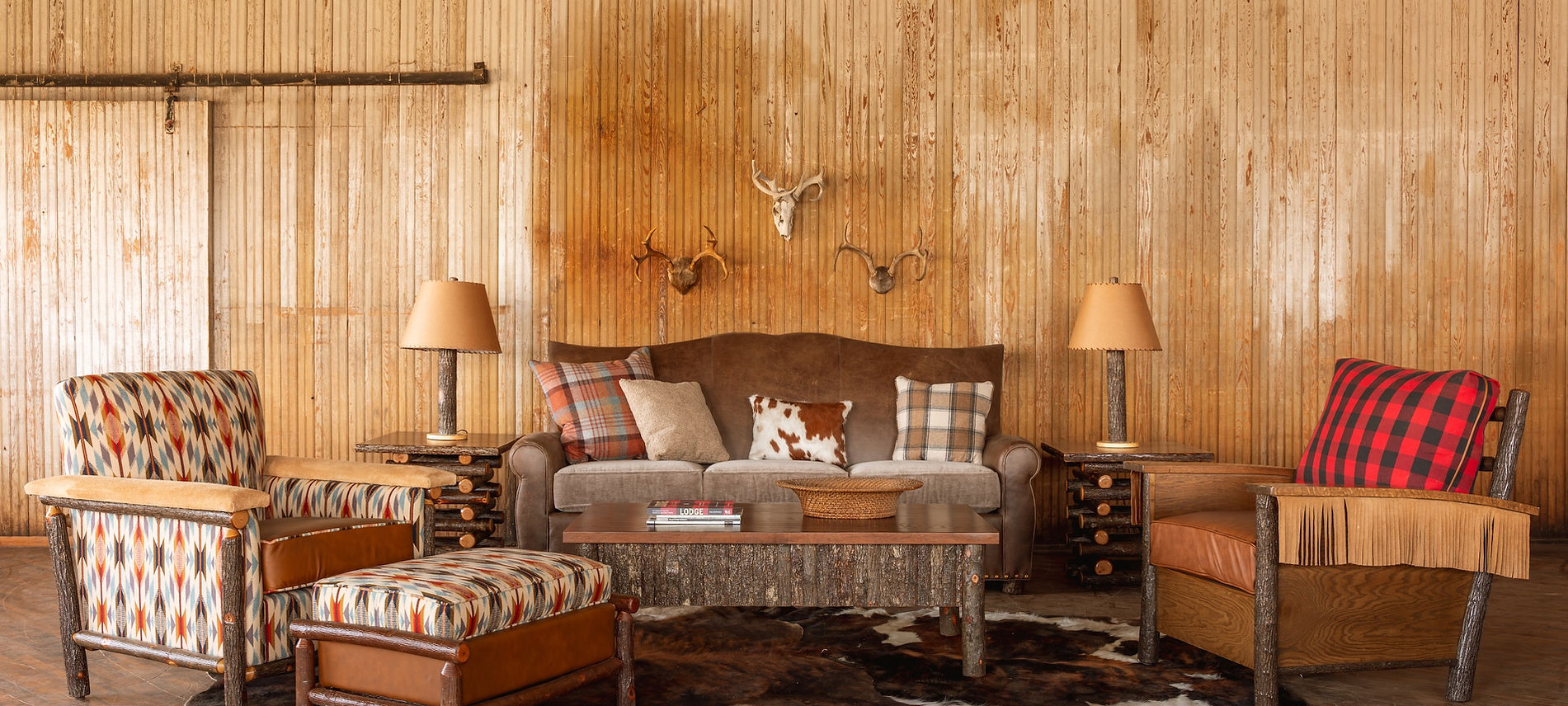 Wooden living room with rustic decor, including a sofa, chairs, and lamps.